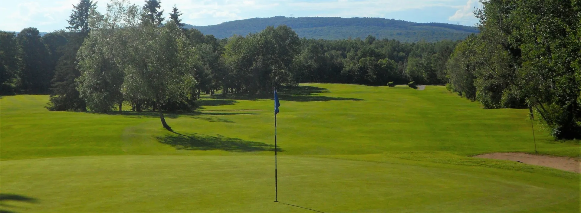 Vert de golf ouvert sur un boisé et des collines